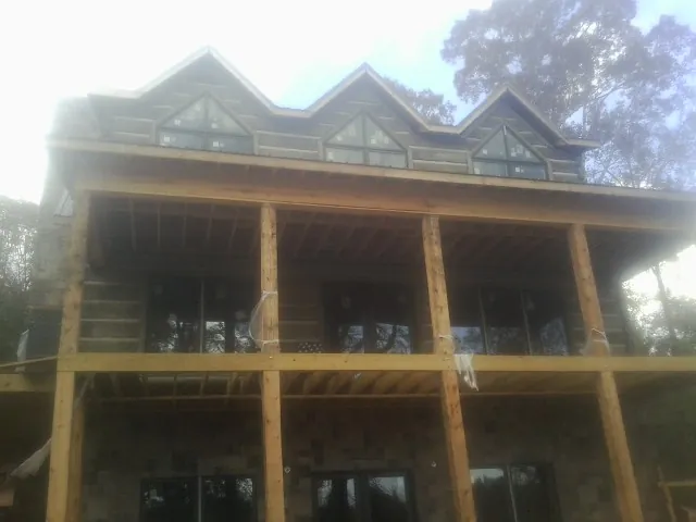 Dormers and porch framing on a large log home under construction — Roof Coating work by our crew in Norway