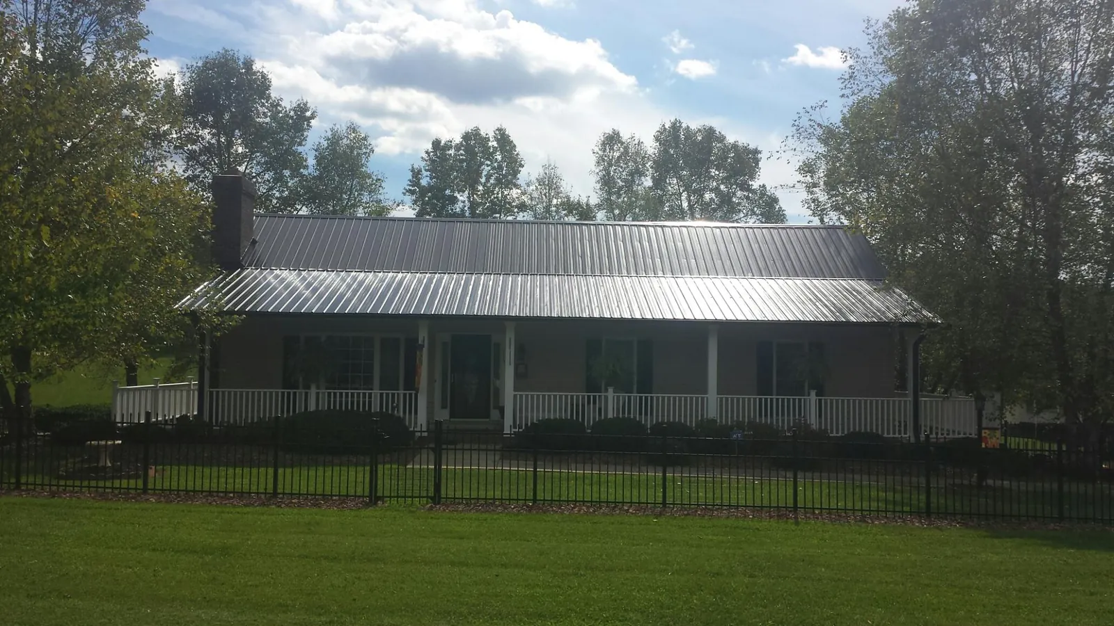 Gray metal roof on a brick ranch with a full width front porch — Gutter Guard Installation work by our crew in Norway