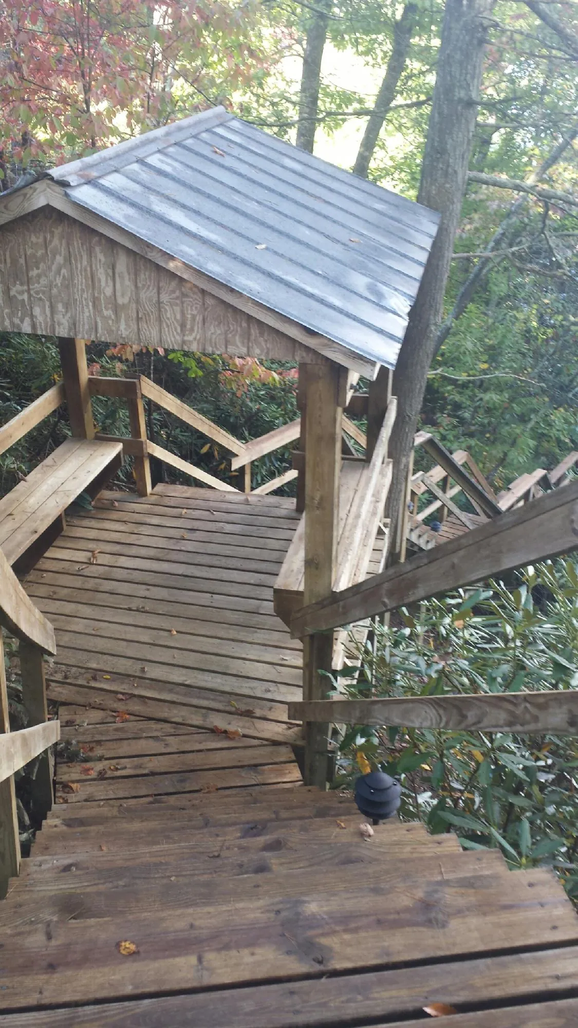 Metal roofed shelter over wooden steps on a wooded walkway — Skylight Repair & Installation work by our crew in Norway