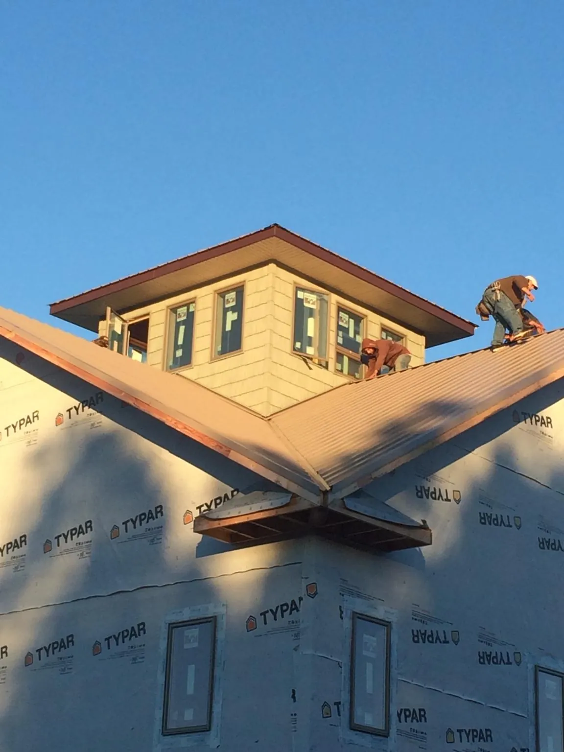 Roofers working around a rooftop cupola on a new metal roof at sunset — Roof Waterproofing in Norway by Roofing Brothers